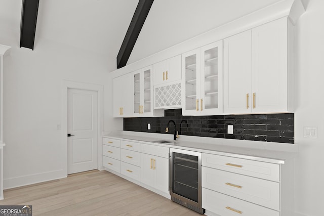 kitchen featuring sink, white cabinetry, light hardwood / wood-style floors, beverage cooler, and beamed ceiling