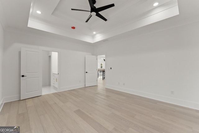 spare room with crown molding, ceiling fan, a raised ceiling, and light wood-type flooring