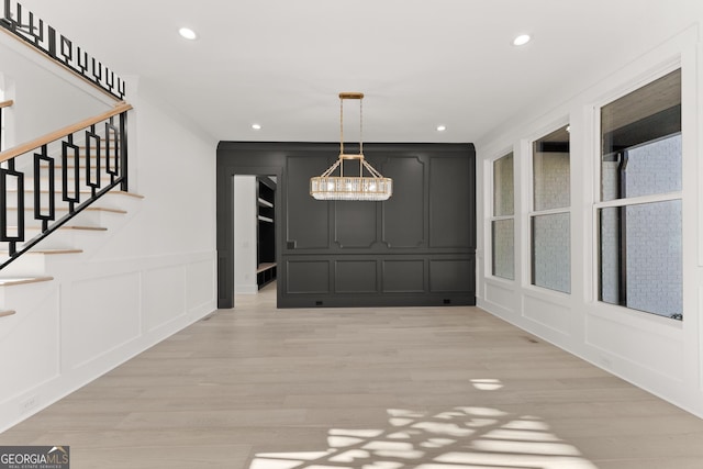 1041 Fleeman Rd, Hoschton, GA 30548 - unfurnished dining area featuring a decorative wall, a chandelier, light wood-type flooring, recessed lighting, and stairs