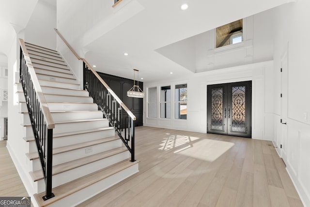 foyer with french doors, a chandelier, and light hardwood / wood-style floors