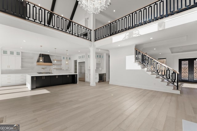 unfurnished living room with a notable chandelier, light hardwood / wood-style floors, and a high ceiling