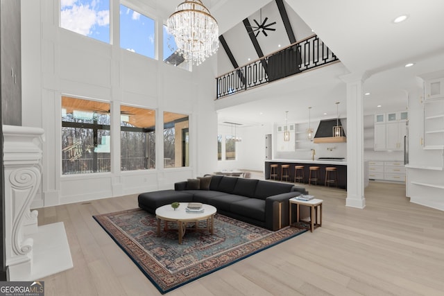 1041 Fleeman Rd, Hoschton, GA 30548 - living area featuring a chandelier, light wood-style floors, a high ceiling, ornate columns, and recessed lighting
