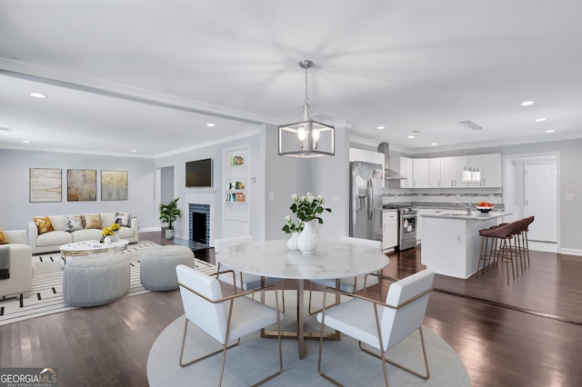 dining space with crown molding, an inviting chandelier, dark hardwood / wood-style flooring, and sink