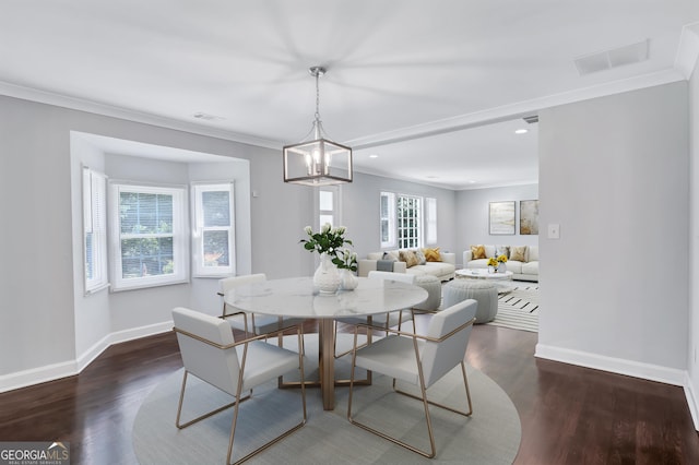 dining room featuring dark wood-type flooring, crown molding, and a chandelier