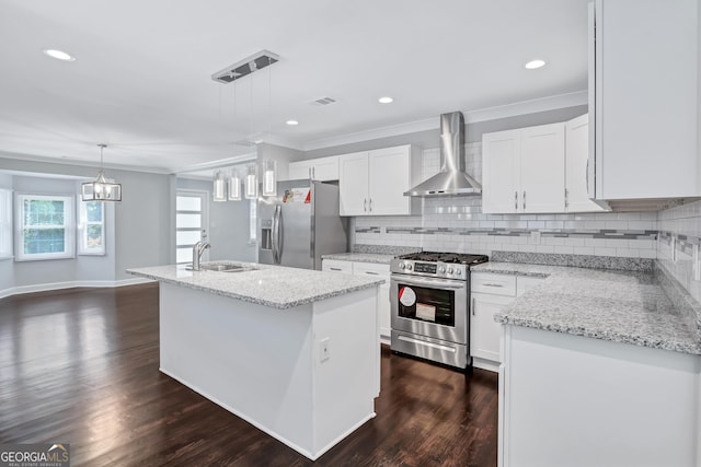 kitchen with pendant lighting, white cabinetry, stainless steel appliances, an island with sink, and wall chimney exhaust hood