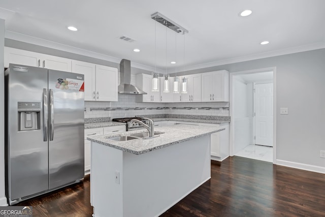 kitchen with sink, decorative light fixtures, a center island with sink, stainless steel fridge, and wall chimney range hood