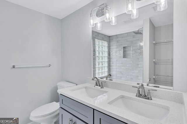 bathroom with vanity, toilet, and a tile shower