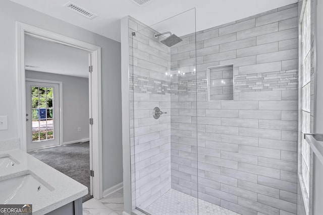 bathroom with tiled shower and vanity