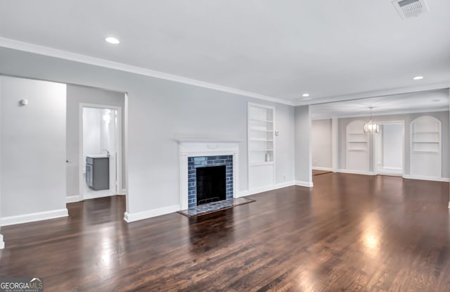 unfurnished living room with dark hardwood / wood-style flooring, built in shelves, a fireplace, and crown molding