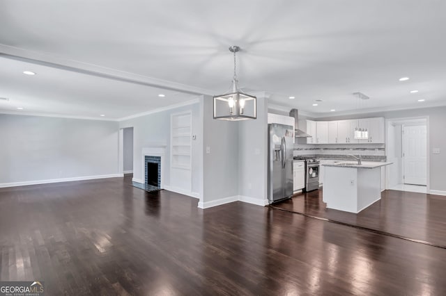 kitchen with light stone counters, decorative light fixtures, a center island, stainless steel appliances, and white cabinets