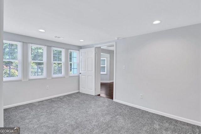 unfurnished bedroom featuring multiple windows and dark carpet