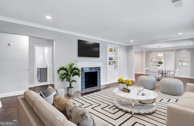 living room featuring hardwood / wood-style flooring, ornamental molding, built in features, and a tile fireplace