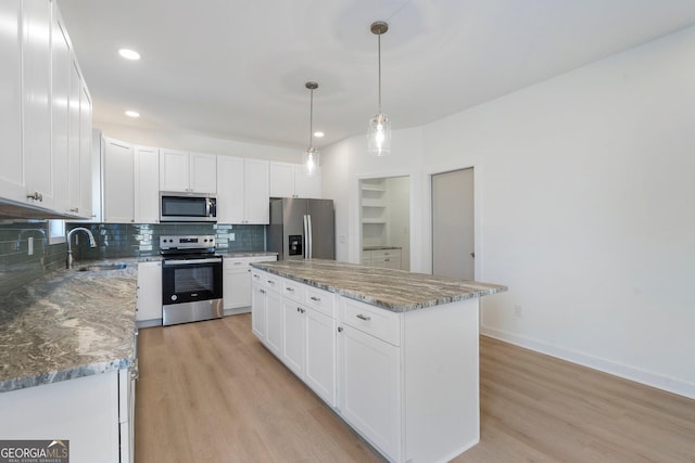 kitchen featuring white cabinetry, stainless steel appliances, sink, and a kitchen island