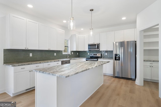 kitchen featuring sink, appliances with stainless steel finishes, a center island, light stone counters, and white cabinets