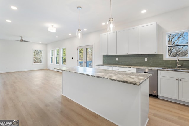 kitchen featuring sink, white cabinetry, hanging light fixtures, a center island, and stainless steel dishwasher