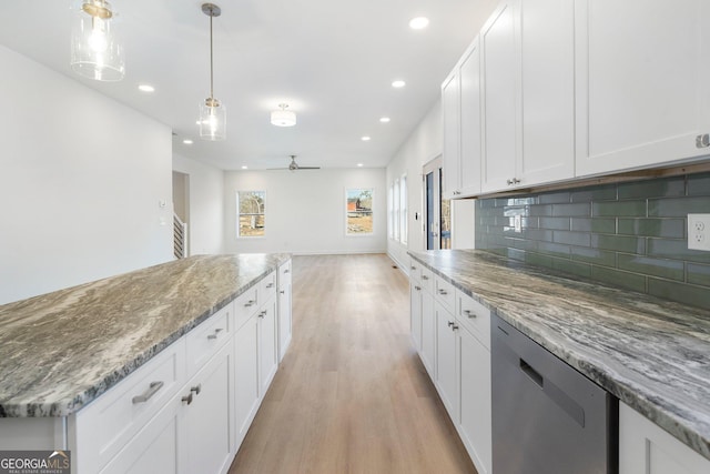 kitchen featuring white cabinetry, backsplash, light stone counters, light hardwood / wood-style floors, and stainless steel dishwasher