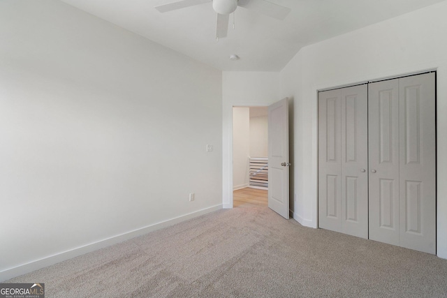 unfurnished bedroom featuring vaulted ceiling, light carpet, ceiling fan, and a closet