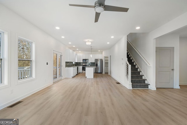 unfurnished living room featuring ceiling fan and light hardwood / wood-style flooring