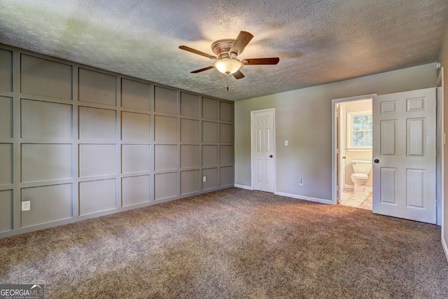 unfurnished bedroom featuring ceiling fan, carpet floors, a textured ceiling, and ensuite bath