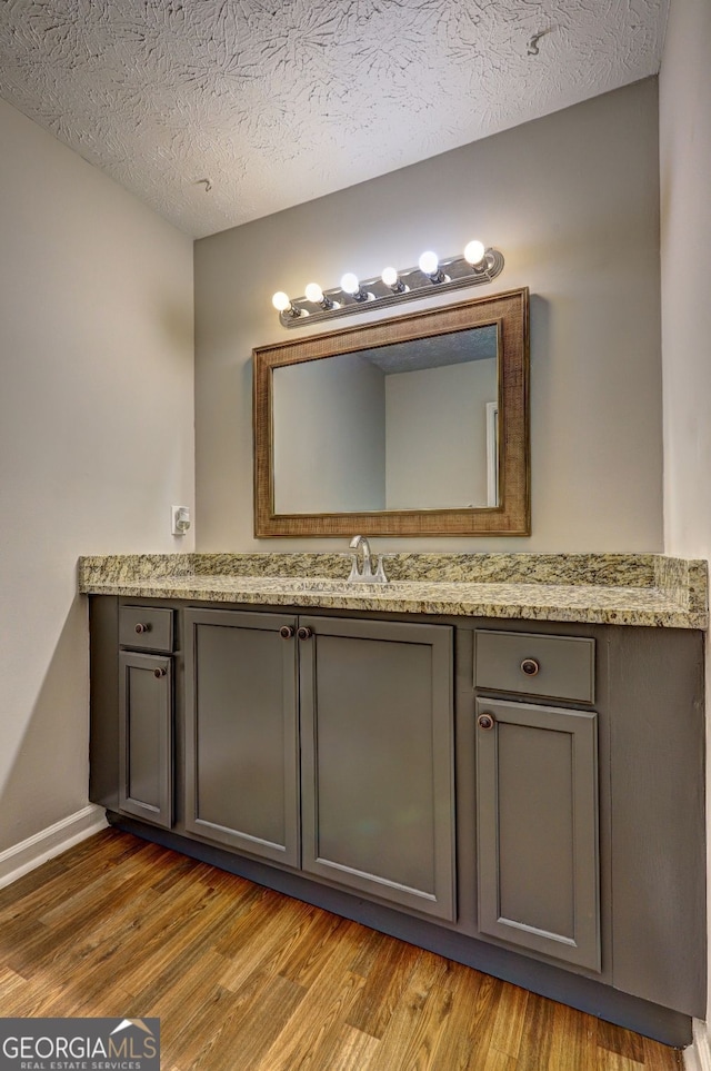 bathroom with vanity, wood-type flooring, and a textured ceiling