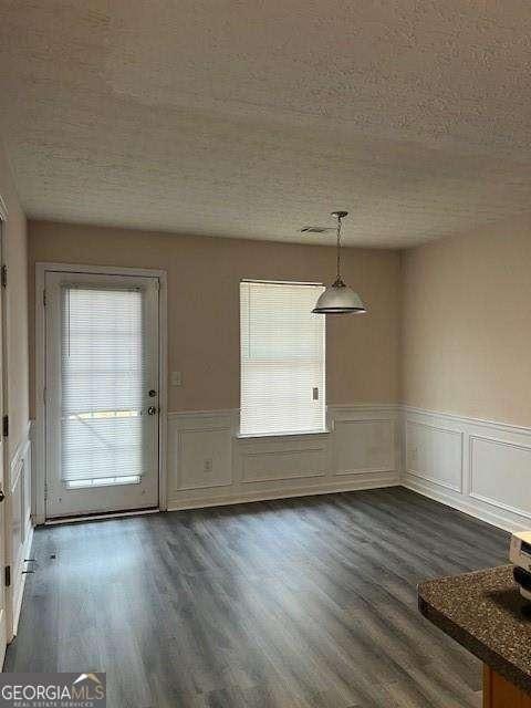 unfurnished dining area with dark hardwood / wood-style flooring and a textured ceiling