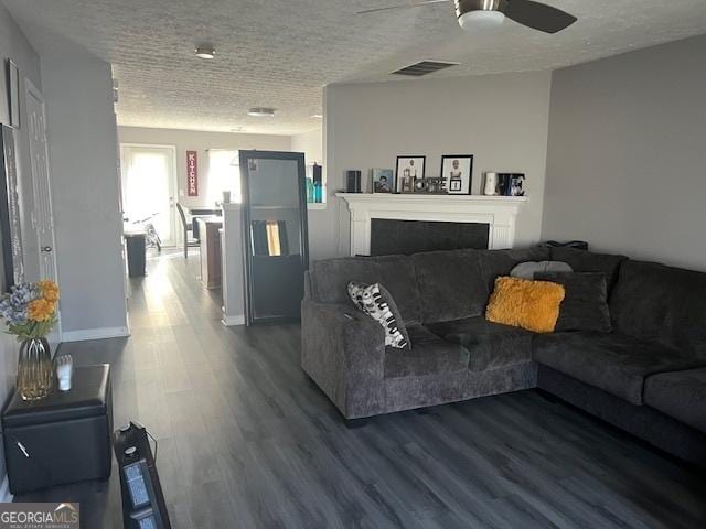 living room featuring ceiling fan, wood-type flooring, and a textured ceiling