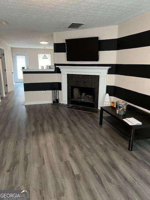 unfurnished living room featuring hardwood / wood-style floors, a fireplace, and a textured ceiling