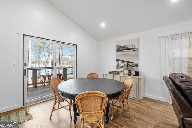 dining room featuring high vaulted ceiling and light wood-type flooring