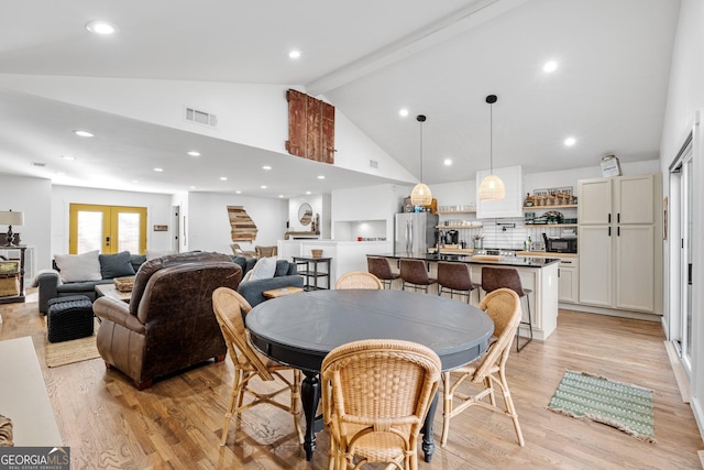 dining area featuring beam ceiling, light hardwood / wood-style flooring, high vaulted ceiling, and french doors