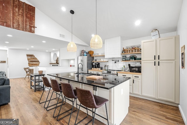 kitchen with sink, appliances with stainless steel finishes, white cabinetry, a center island with sink, and a kitchen bar