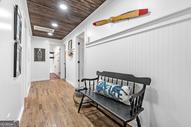 hall with hardwood / wood-style flooring, ornamental molding, and wooden ceiling