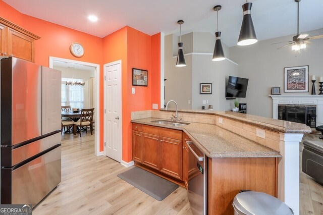 kitchen featuring light stone counters, stainless steel dishwasher, sink, and pendant lighting