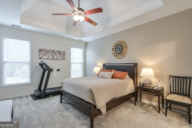 carpeted bedroom featuring ceiling fan and a tray ceiling