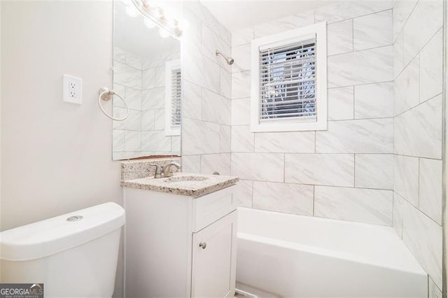 full bathroom with vanity, tiled shower / bath combo, and toilet