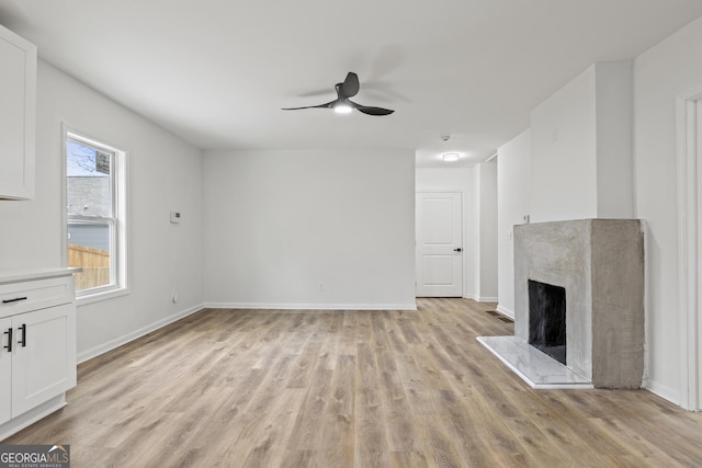 unfurnished living room with ceiling fan, a fireplace, and light hardwood / wood-style floors