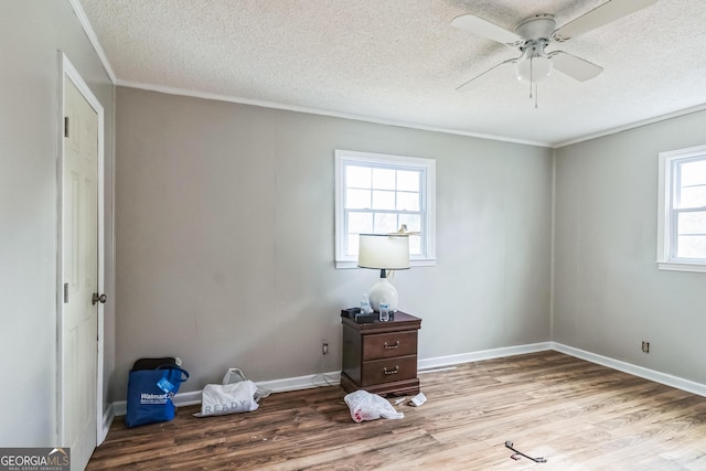 unfurnished room featuring ceiling fan, crown molding, light hardwood / wood-style floors, and a textured ceiling