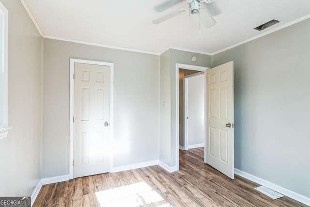 unfurnished bedroom with hardwood / wood-style flooring, ornamental molding, and ceiling fan