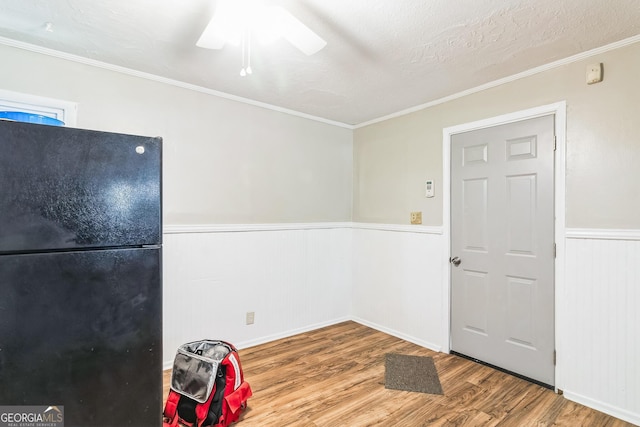 interior space featuring black fridge, crown molding, hardwood / wood-style floors, and a textured ceiling