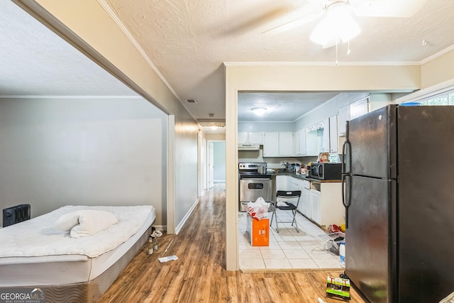 kitchen with white cabinetry, light hardwood / wood-style flooring, ornamental molding, and appliances with stainless steel finishes