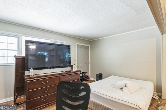 bedroom with hardwood / wood-style flooring, crown molding, and a textured ceiling