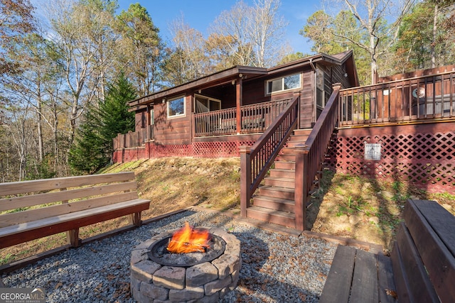 back of property with an outdoor fire pit and a deck