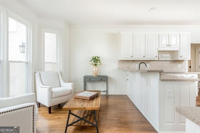 kitchen with a breakfast bar, crown molding, dark hardwood / wood-style floors, decorative backsplash, and white cabinets