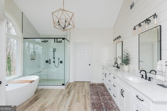 bathroom with lofted ceiling, an inviting chandelier, vanity, plus walk in shower, and hardwood / wood-style floors