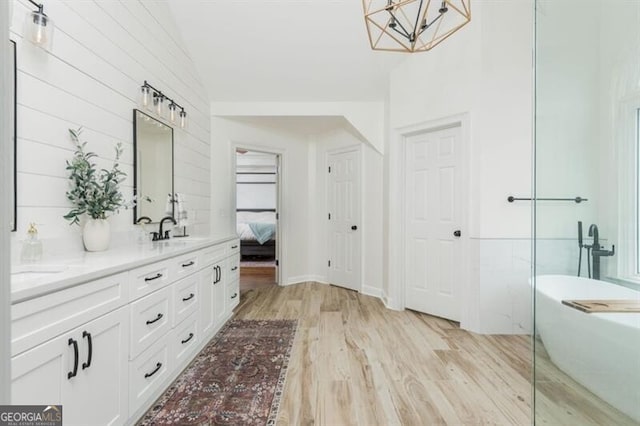 bathroom featuring wood-type flooring, vanity, and a tub