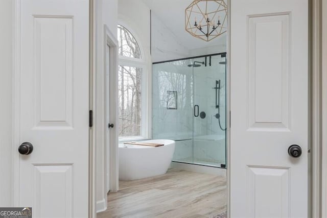 bathroom with hardwood / wood-style flooring, shower with separate bathtub, and a notable chandelier