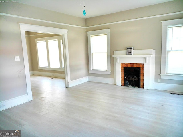 unfurnished living room featuring a brick fireplace and light hardwood / wood-style flooring