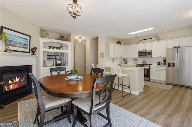 dining room with an inviting chandelier, sink, and light hardwood / wood-style floors