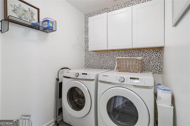 clothes washing area featuring cabinets and washer and clothes dryer