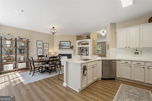 kitchen with sink, stainless steel dishwasher, kitchen peninsula, and white cabinets