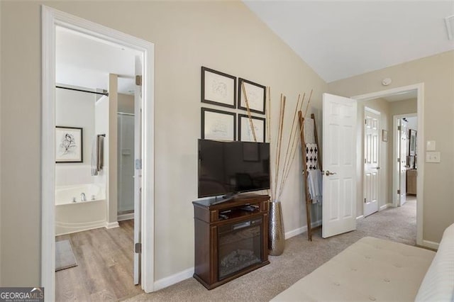 carpeted bedroom featuring lofted ceiling and connected bathroom